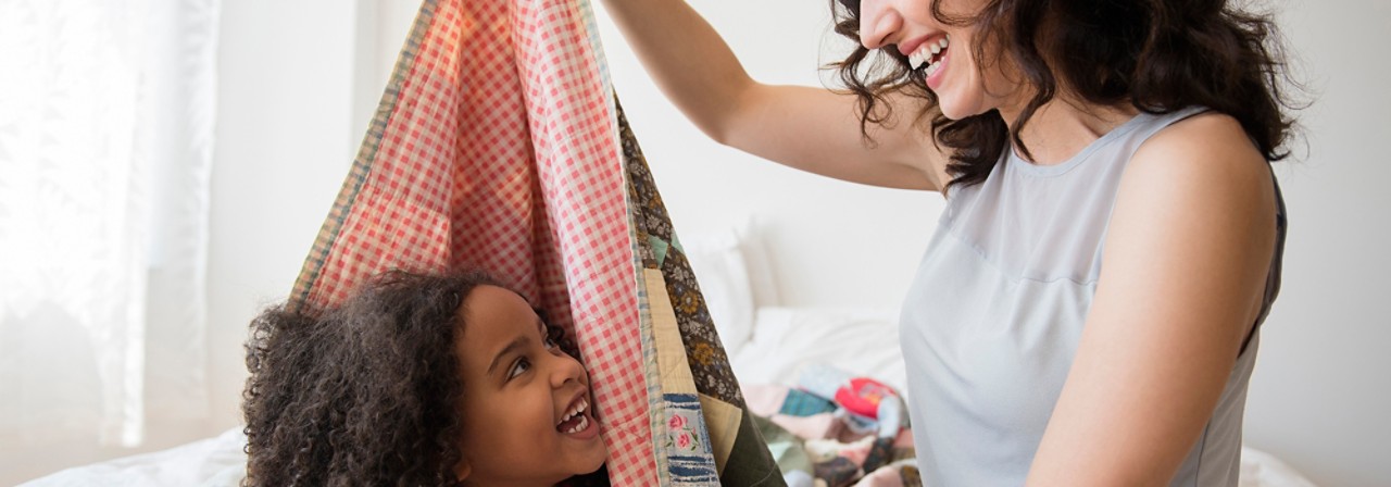Mother and daughter playing in blanket fort