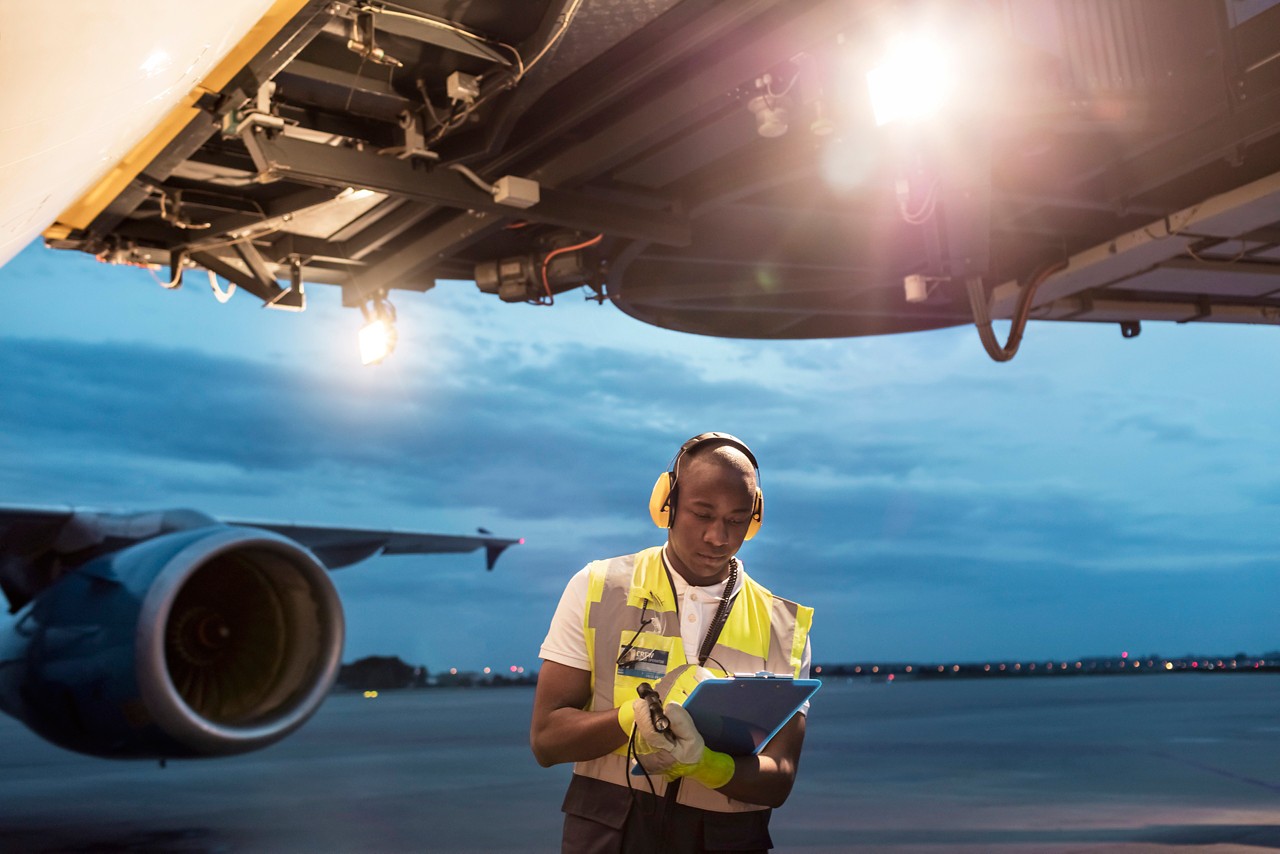 airport ground crew standing below airplane on tarmac
