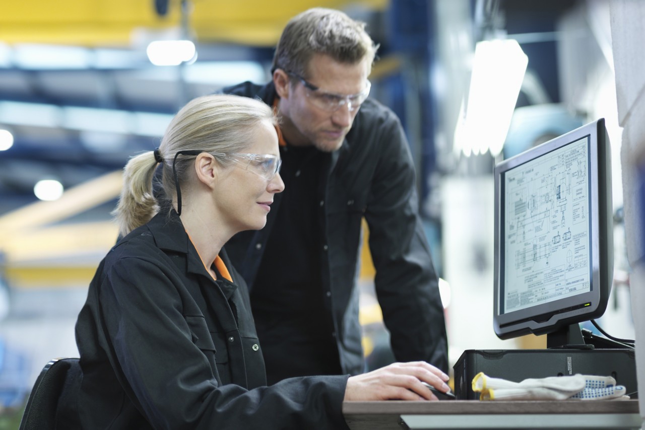 Engineers using computer to work on plans in engineering factory, service and support
