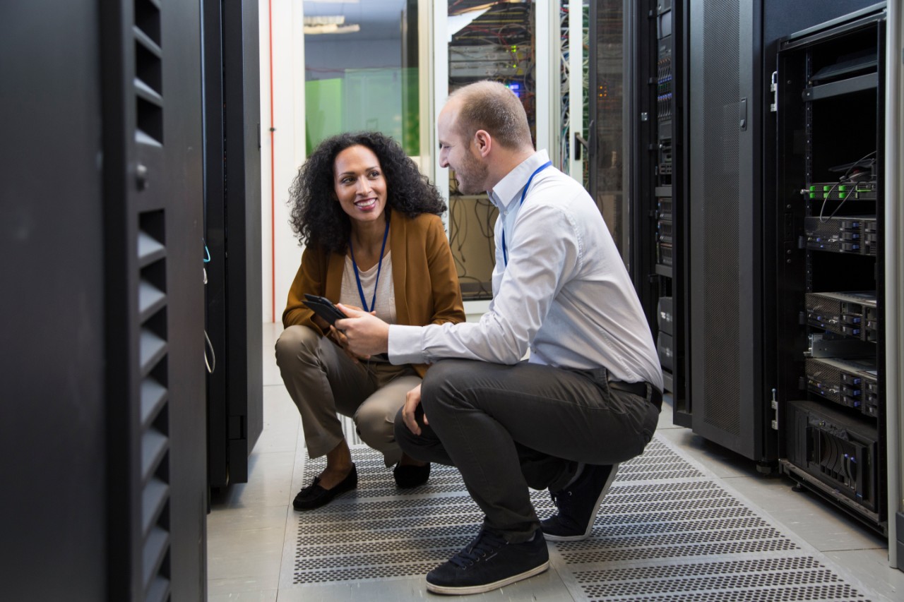 Computer technicians working on digital tablet in server room.