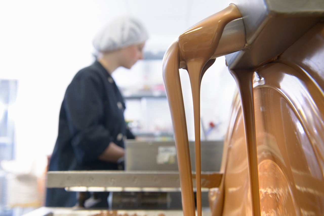 Liquid chocolate running through machine in sweet factory