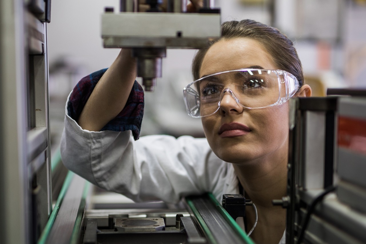 Quality control inspector working on a manufacturing machine in laboratory.