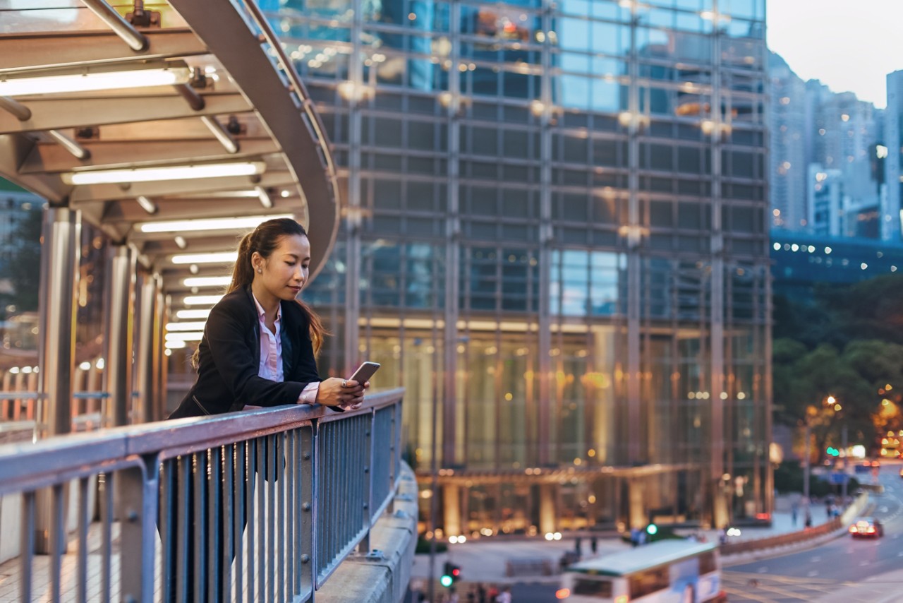 Business woman standing on pedestrian bridge at dusk