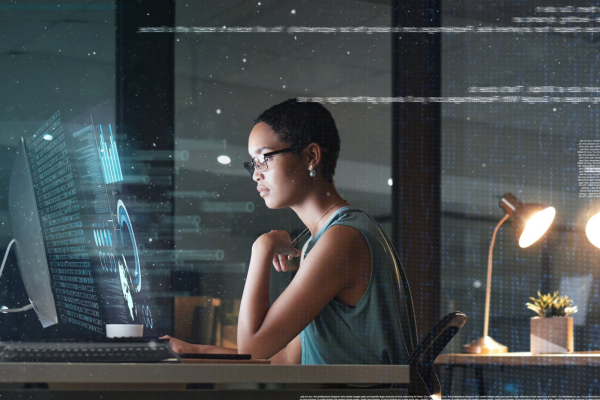 Woman working at desktop computer at night with digital display