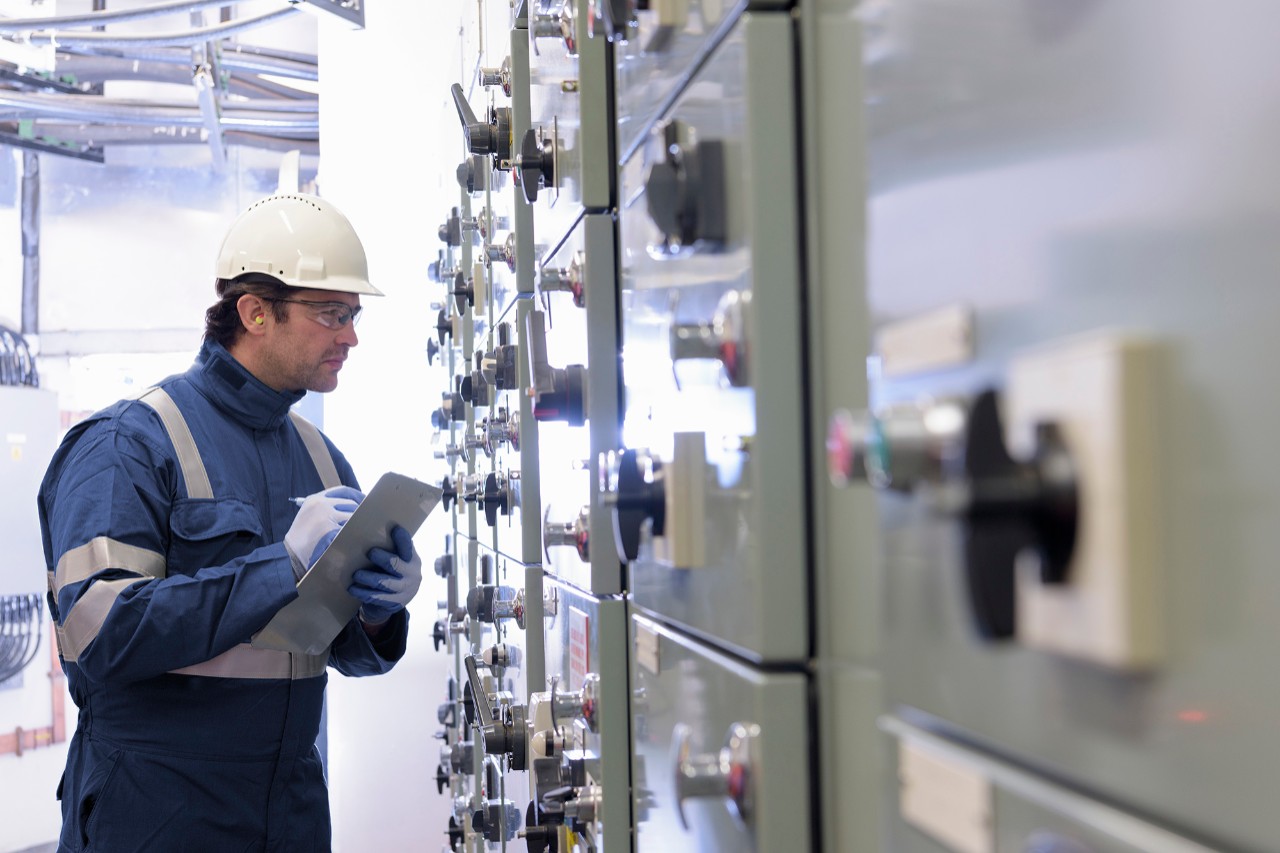Worker inspecting switch gear in hydroelectric power station