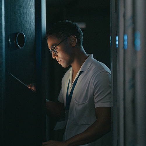 Side view of young man using a digital tablet while working in a data center