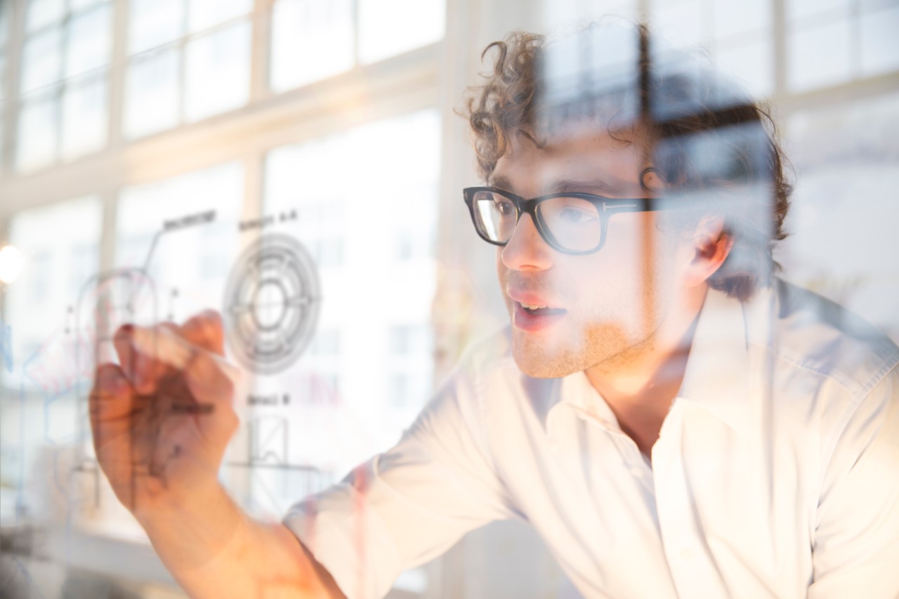 Portrait of young architect marking construction plan in office